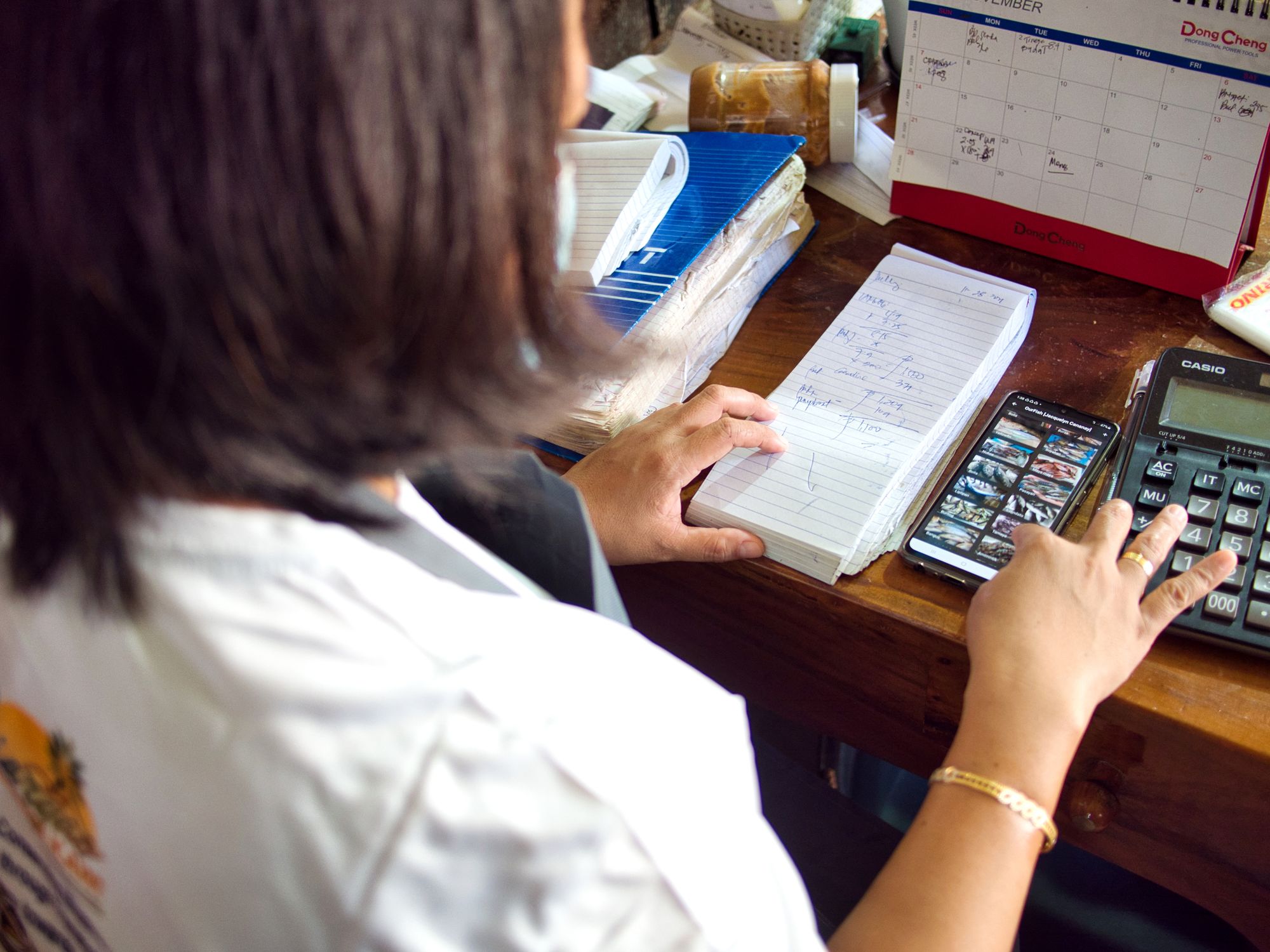 Jacquelyn Caranay, a fish buyer, keeping records and using the OurFish app.