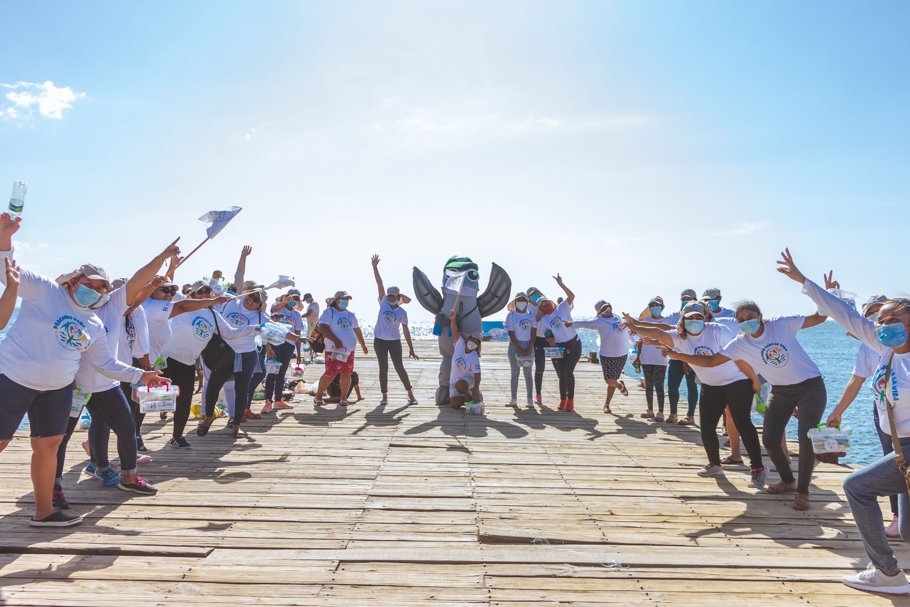 Photo of a fish mascot on a pier with people happily around it.